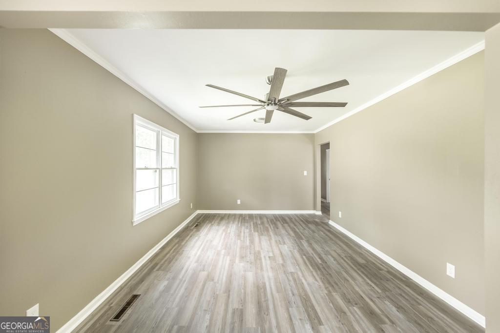 208 South 6th Street Vienna, GA 31092 - Photo 4 of 29 an empty room with wooden floor fan and windows