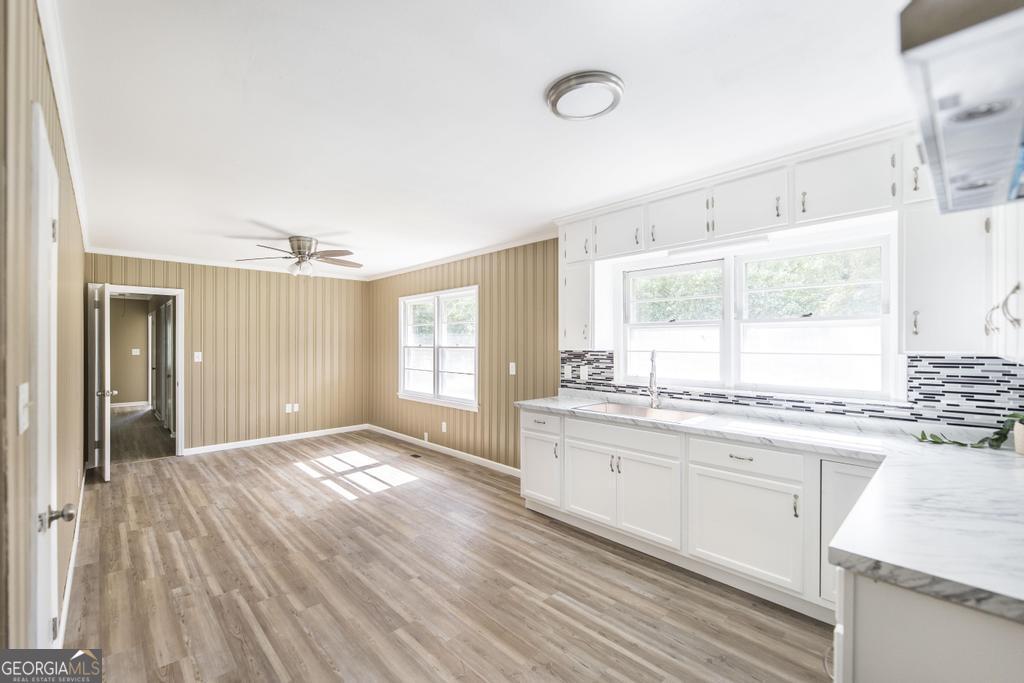 208 South 6th Street Vienna, GA 31092 - Photo 8 of 29 a kitchen with granite countertop a stove a sink and white cabinets with wooden floor