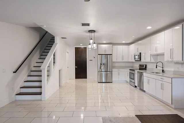a kitchen with stainless steel appliances kitchen island granite countertop a refrigerator and a sink