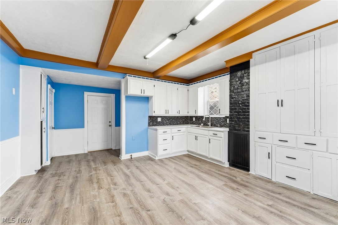 563 Geneva Avenue Struthers, OH 44471 - Photo 6 of 31 Kitchen with beam ceiling, white cabinets, a wainscoted wall, light wood finished floors, and light countertops