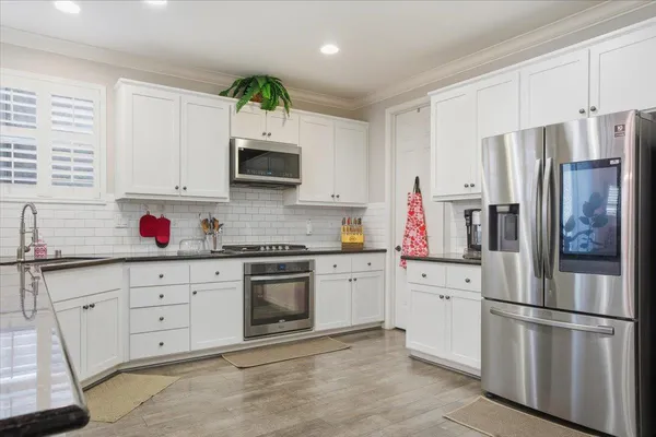 a kitchen with granite countertop stainless steel appliances a sink cabinets and a window