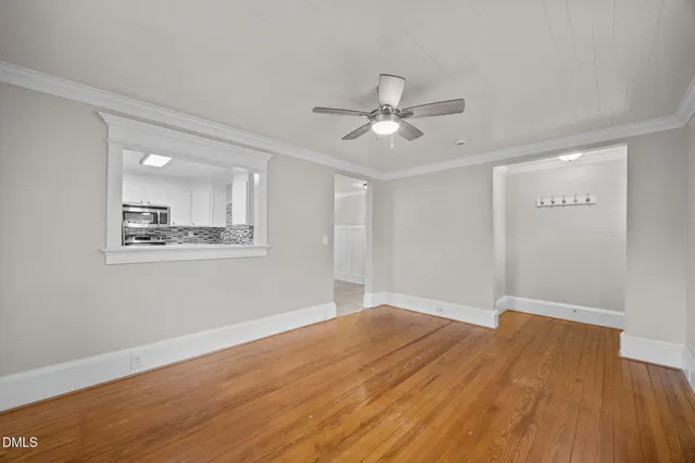 a view of empty room with wooden floor and fan