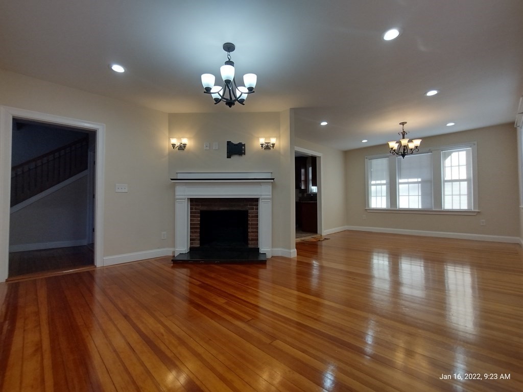 62 Washington Street, Unit 62 Wellesley, MA 02481 - Photo 4 of 18 a view of an empty room with wooden floor fireplace and a window