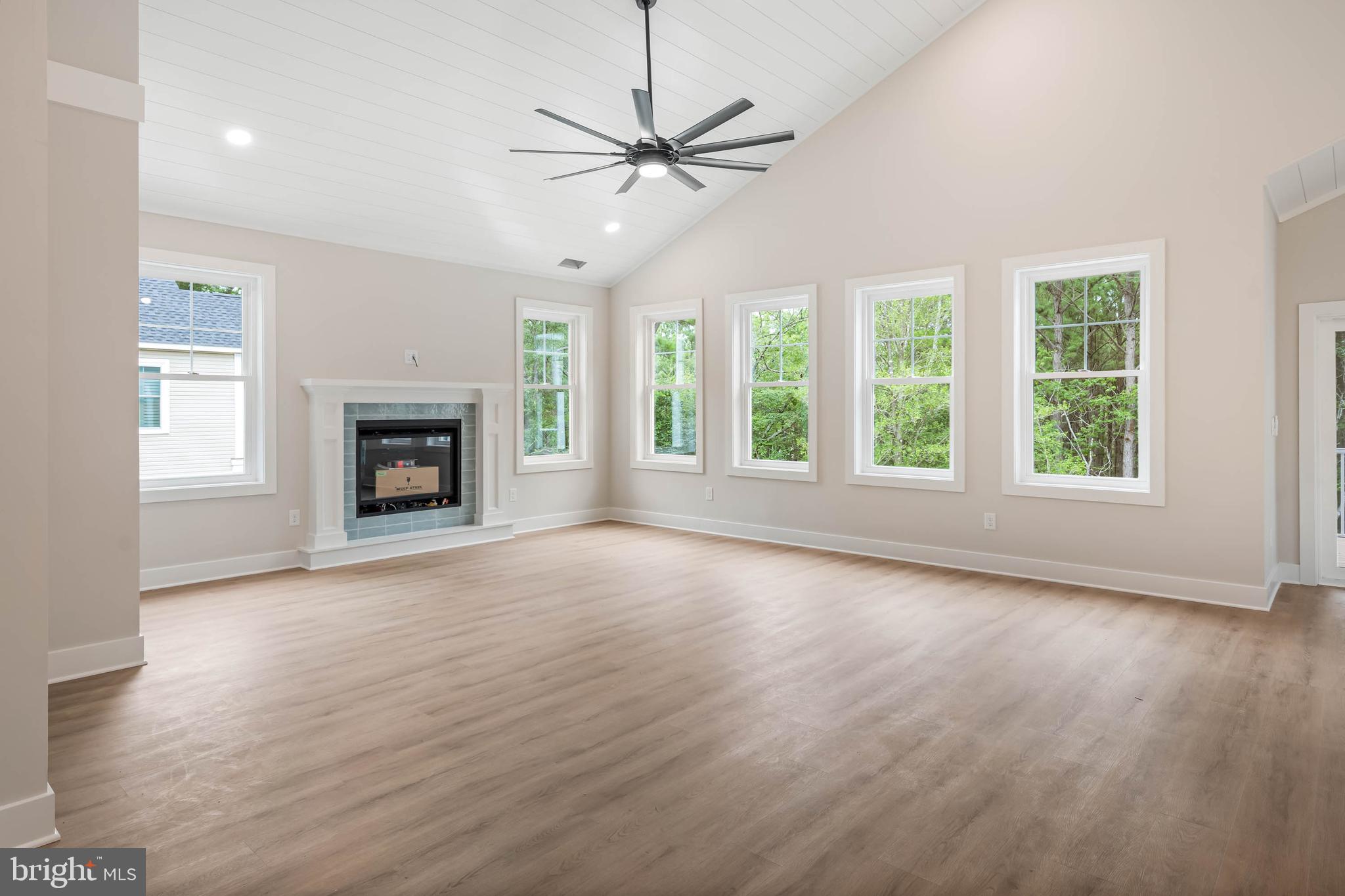 38697 Fred Hudson Road Bethany Beach, DE 19930 - Photo 31 of 51 an empty room with windows a fireplace and a ceiling fan