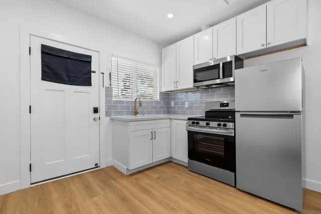 a kitchen with stainless steel appliances white cabinets and a refrigerator