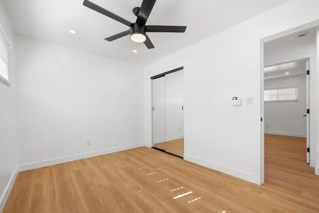 an empty room with wooden floor and a ceiling fan