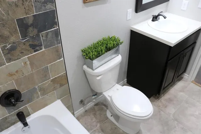 a white toilet sitting next to a bathroom sink and a mirror