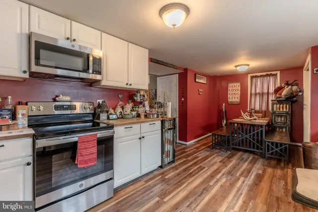 a kitchen with stainless steel appliances kitchen island granite countertop a stove top oven a sink dishwasher a dining table and chairs with wooden floor