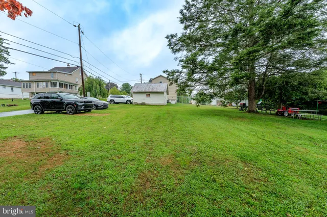 a view of a house with a big yard and large trees
