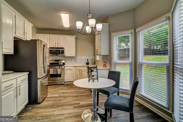 a kitchen with stainless steel appliances kitchen island granite countertop a dining table chairs refrigerator and sink