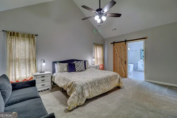 a bedroom with a large bed couch and windows