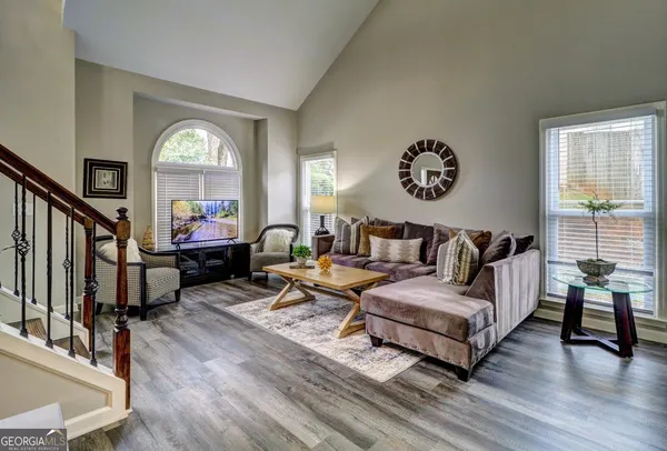 a living room with furniture and a large mirror next to a window