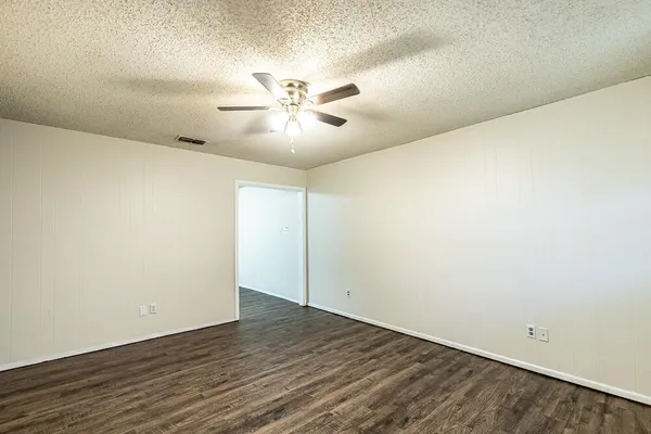 an empty room with wooden floor and fan