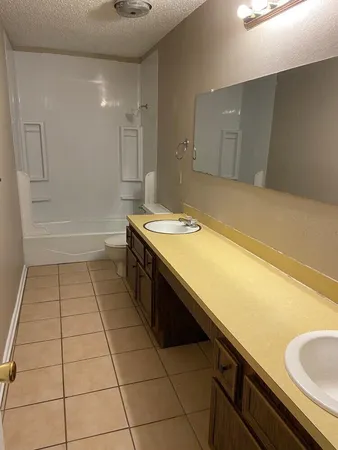 a bathroom with a granite countertop sink a toilet and bathtub