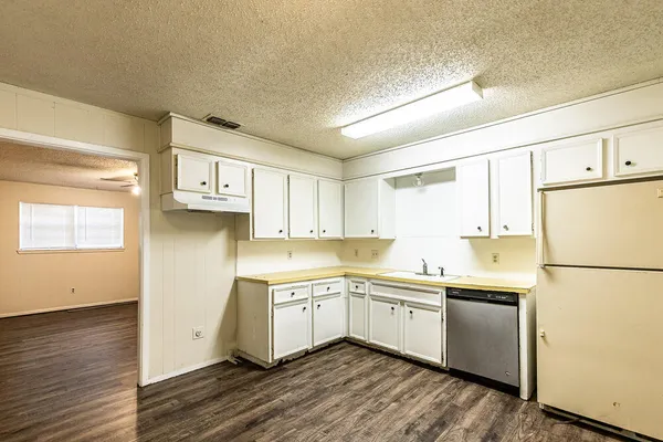 a kitchen with a sink a refrigerator and white cabinets