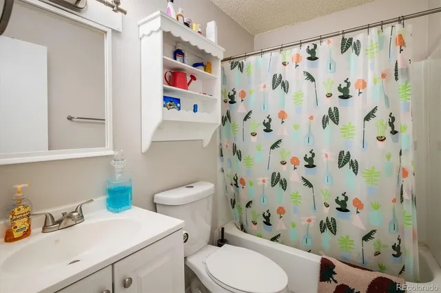 a white toilet sitting next to a sink curtain and a shower curtain