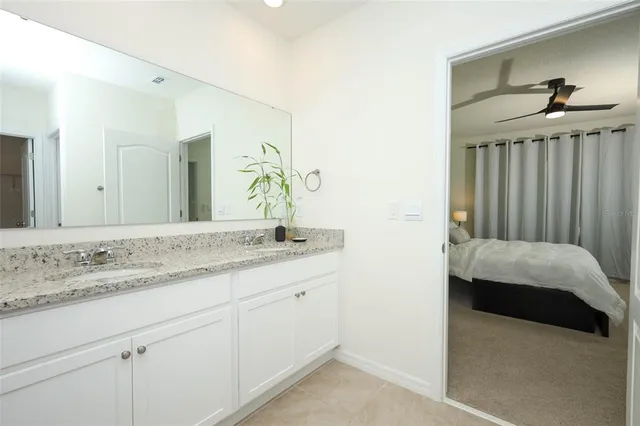 a en suite bathroom with a granite countertop sink and a mirror