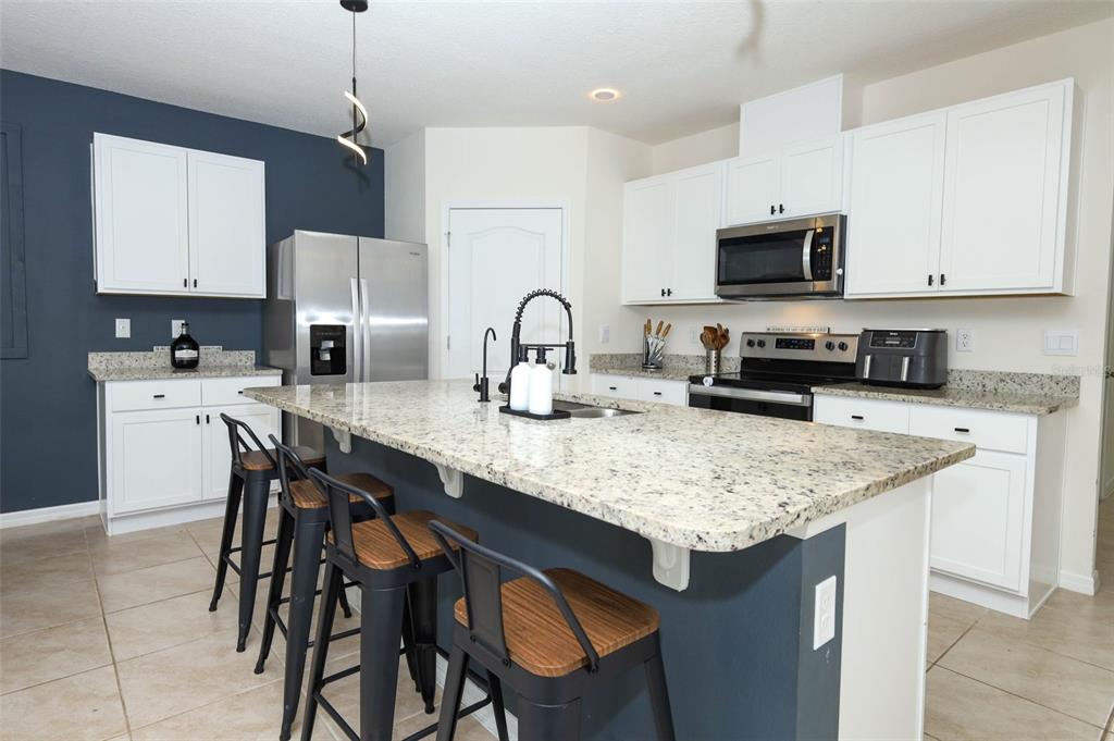 33417 Affirmed Way Sorrento, FL 32776 - Photo 7 of 43 a kitchen with stainless steel appliances granite countertop a table chairs sink refrigerator and microwave