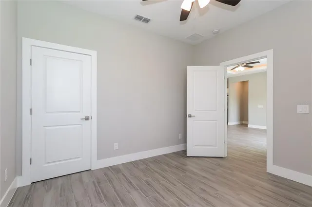 an empty room with wooden floor closet and windows