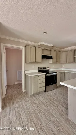a large white kitchen with stainless steel appliances a stove and more cabinets