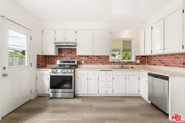 a kitchen with stainless steel appliances white cabinets a stove a sink and a microwave