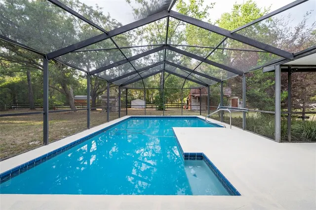 an aerial view of residential house with outdoor space and trees all around
