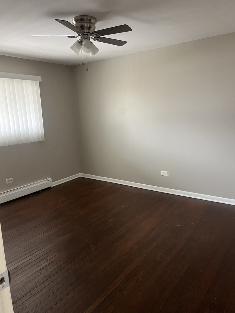 8817 South Roberts Road, Unit 11 Hickory Hills, IL 60457 - Photo 7 of 7 an empty room with wooden floor fan and windows