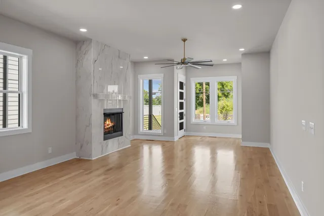 an empty room with wooden floor a ceiling fan and windows