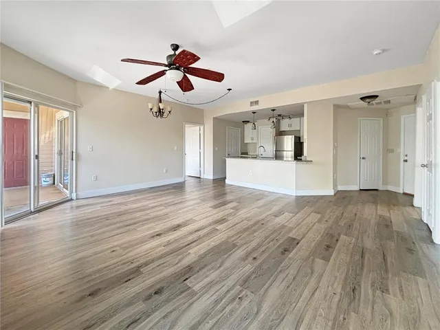 a view of an empty room with wooden floor and a ceiling fan