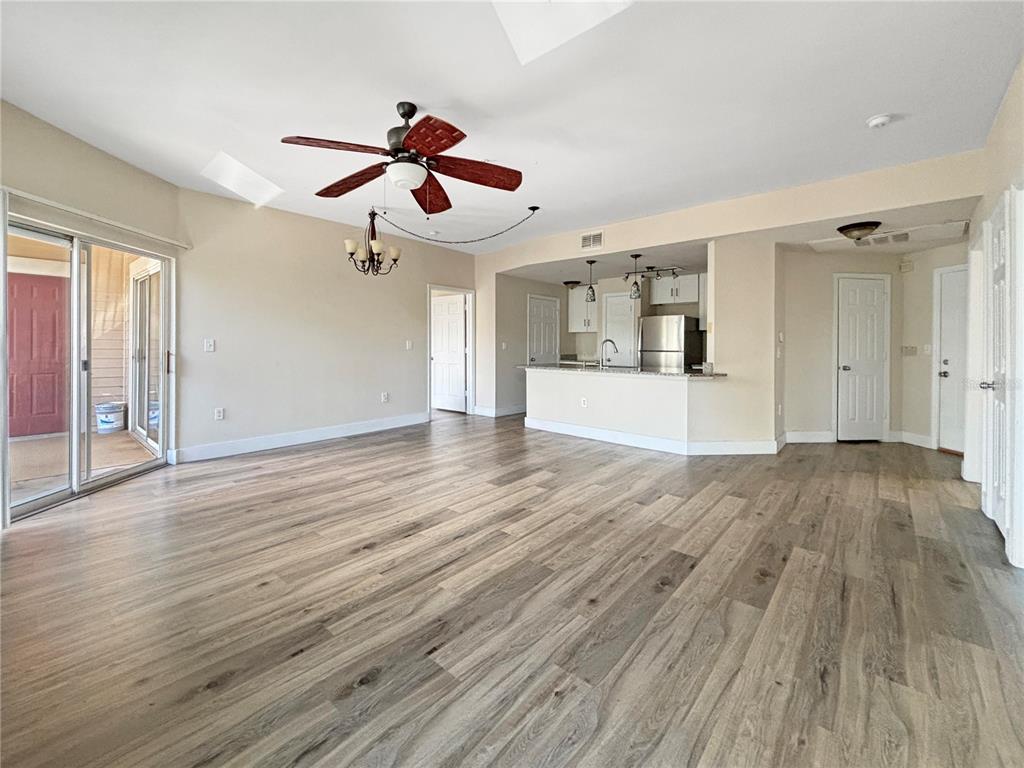 a view of an empty room with wooden floor and a ceiling fan
