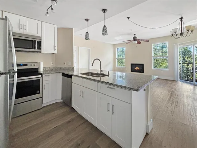 a kitchen with granite countertop a sink stainless steel appliances and cabinets
