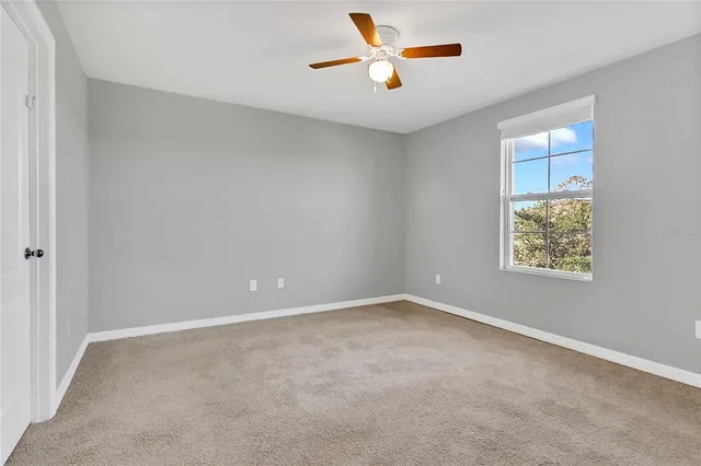 an empty room with a window and a ceiling fan