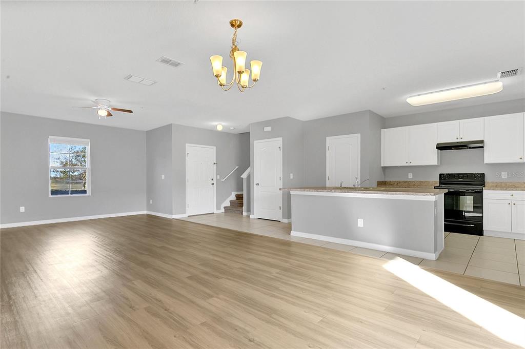 1621 Reflection Cove St. Cloud, FL 34771 - Photo 5 of 35 a view of an empty room and kitchen with wooden floor
