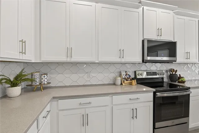 a kitchen with stainless steel appliances white cabinets and a stove top oven