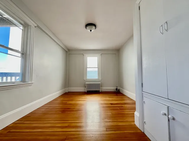 a view of empty room with window and wooden floor