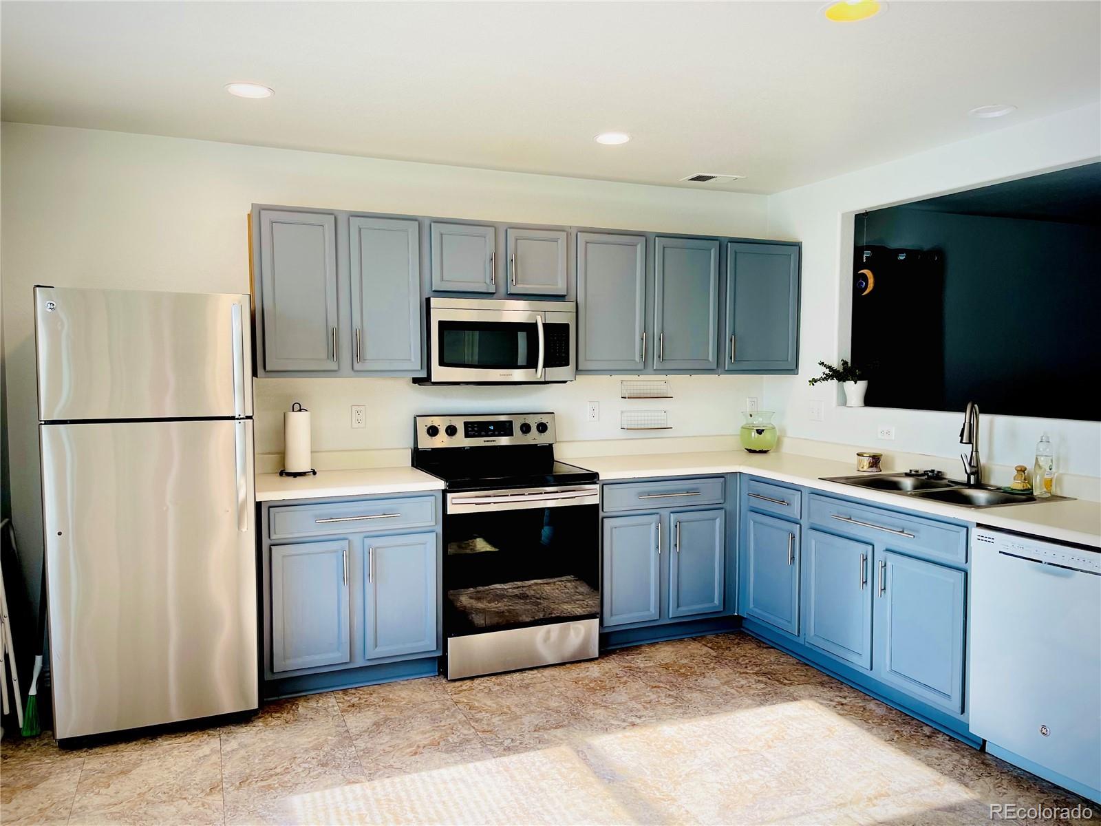 10100 Eudora Court Thornton, CO 80229 - Photo 3 of 17 a kitchen with sink a microwave a refrigerator and cabinets