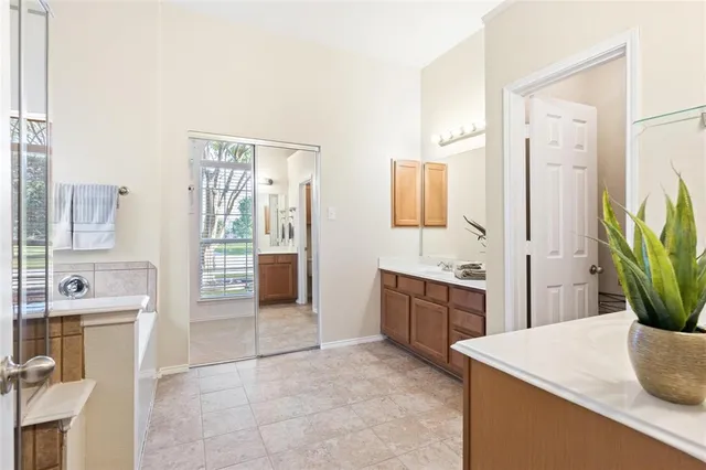 a spacious bathroom with a granite countertop sink a mirror and a bathtub