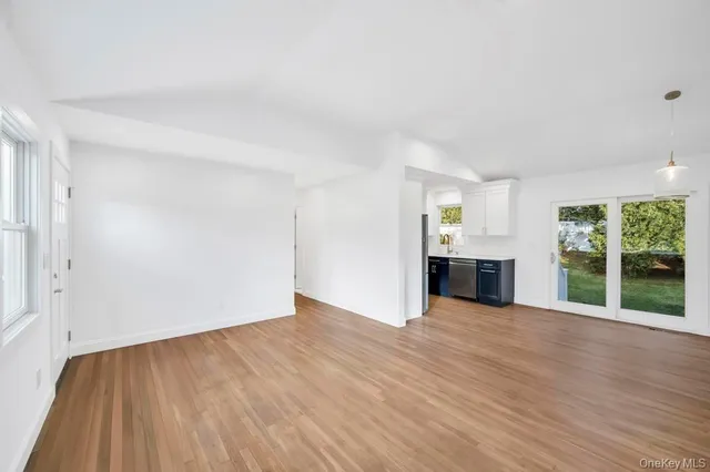 an empty room with wooden floor and natural light