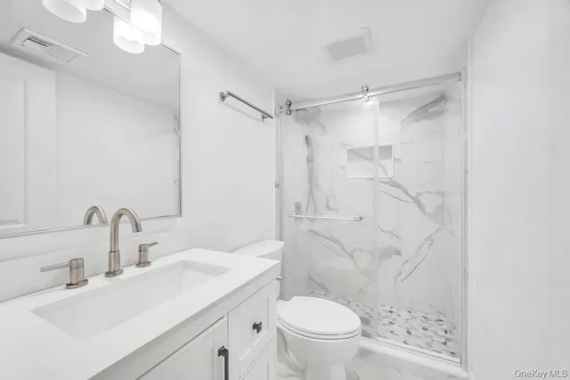 a bathroom with a sink toilet vanity and shower