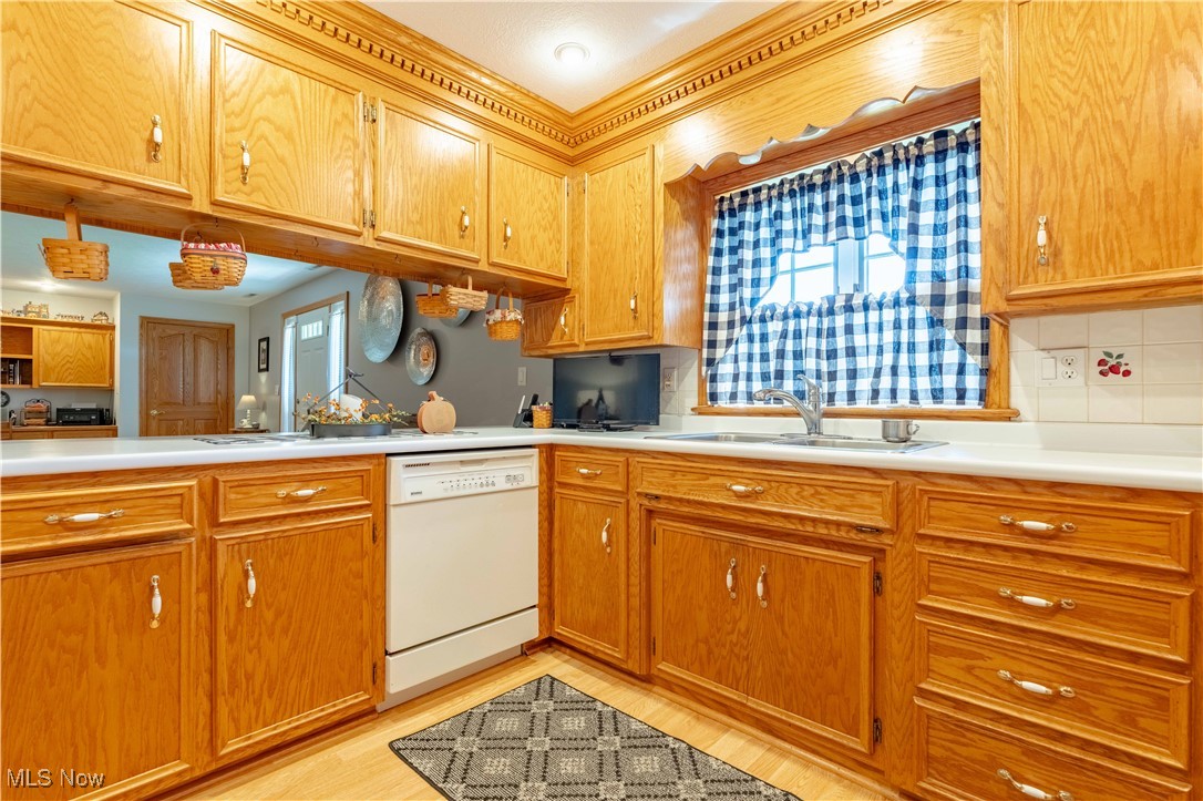 90480 Kilgore Ridge Road Scio, OH 43988 - Photo 10 of 39 Kitchen featuring light countertops, dishwasher, light wood-style floors, brown cabinetry, and tasteful backsplash