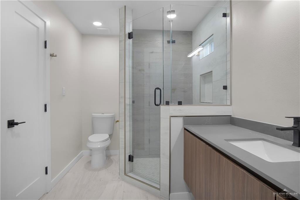 2204 Corales Street Mission, TX 78573 - Photo 11 of 30 a bathroom with a granite countertop sink a toilet and shower