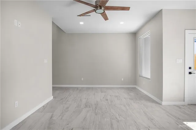 a view of an empty room with a ceiling fan and a window