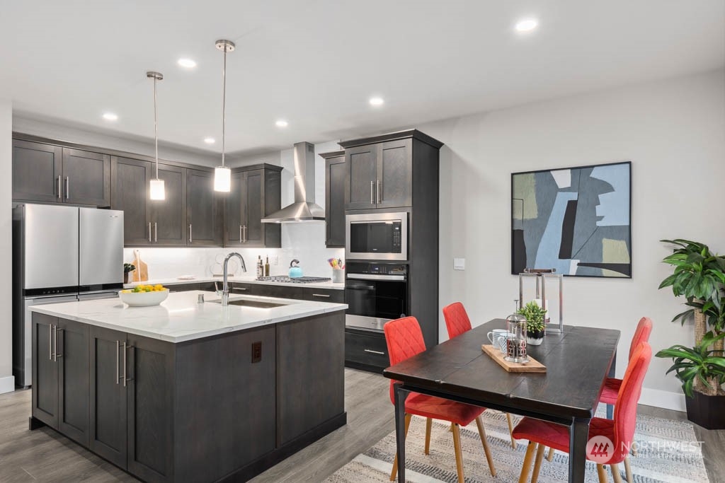 4020 171st Place Southeast Bothell, WA 98012 - Photo 9 of 35 a kitchen with a stove a refrigerator a sink a dining table and chairs with wooden floor