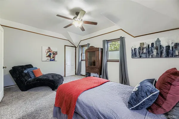 a bedroom with a bed ceiling fan and a dresser
