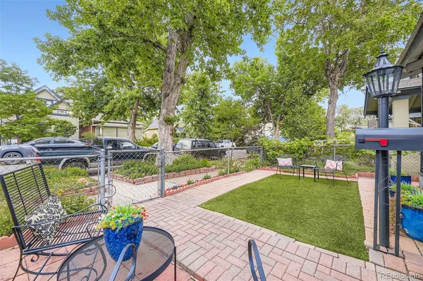 a view of a patio with table and chairs potted plants and large tree