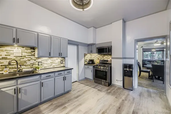 a kitchen with stainless steel appliances kitchen island granite countertop a refrigerator oven a sink dishwasher and white cabinets with wooden floor