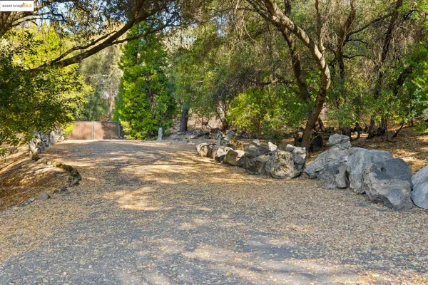 a backyard of a house with large trees and outdoor seating