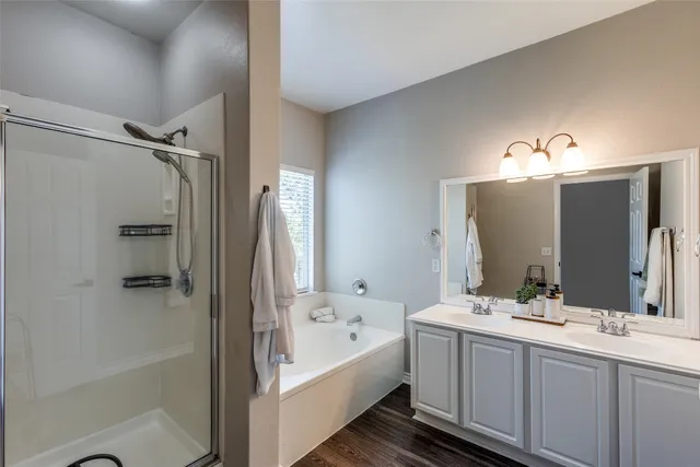 a bathroom with a double vanity sink mirror and bathtub