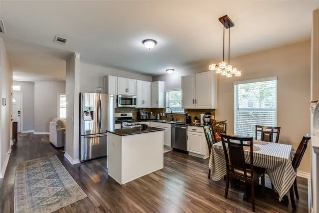 a kitchen with refrigerator a sink dishwasher a stove and a dining table with wooden floor