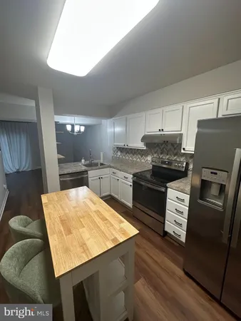 a kitchen with stainless steel appliances kitchen island granite countertop a refrigerator a stove and a sink with wooden floor